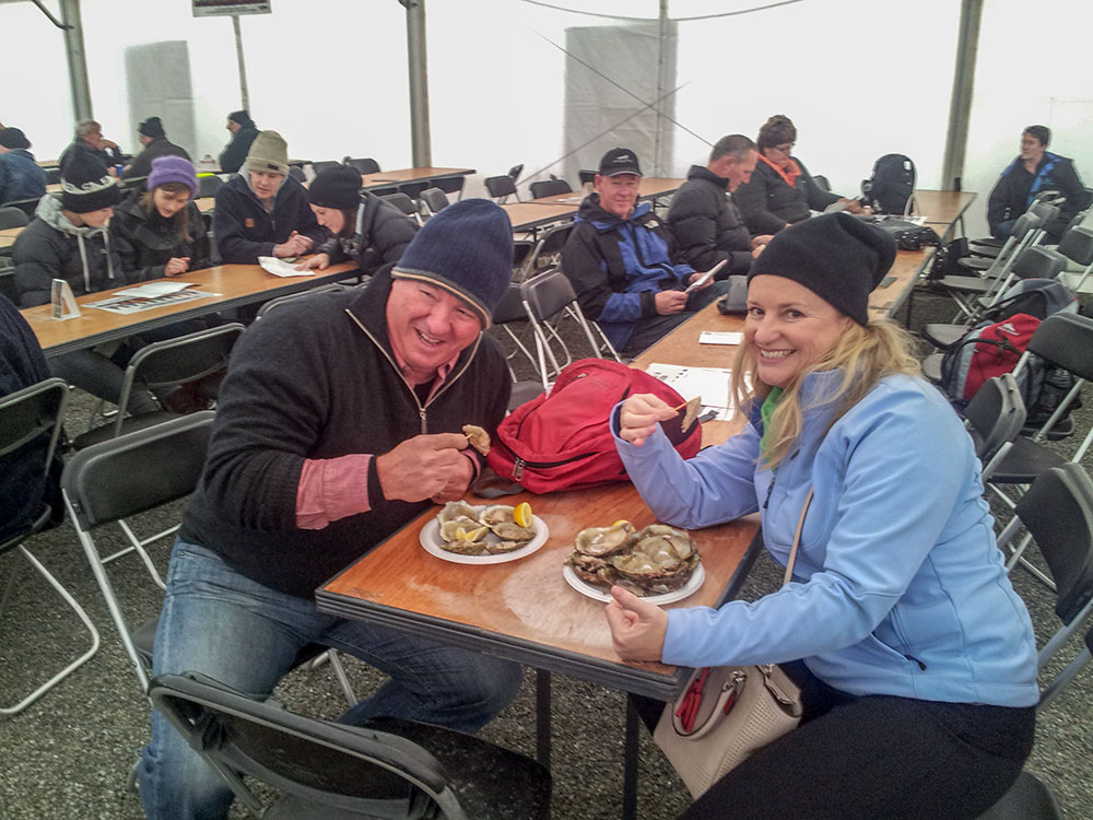 Couple eating fresh raw Bluff oysters at the festival on their tour